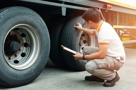 A person kneeling on a truck tire Description automatically generated